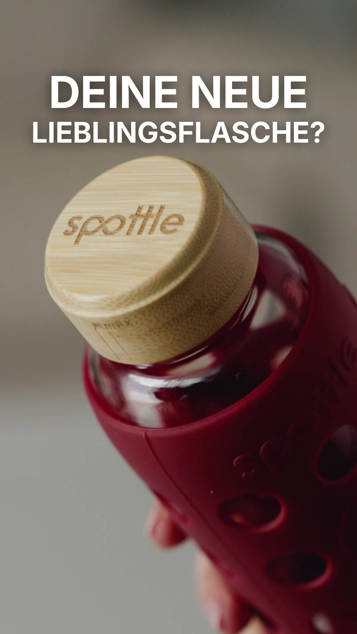 Eine spottle Glasflasche mit Silikonhülle in Berry wird ausgepackt, mit Wasser befüllt und ohne Deckel in die Spülmaschine gestellt.
